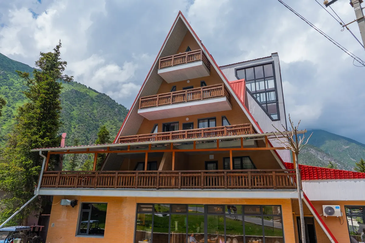 The front of the red-roofed “Ala-Archa” building, with wooden balconies on three floors under its steep gable.