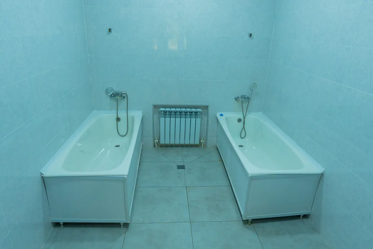 A tiled treatment room at Teplye Klyuchi with two individual baths.