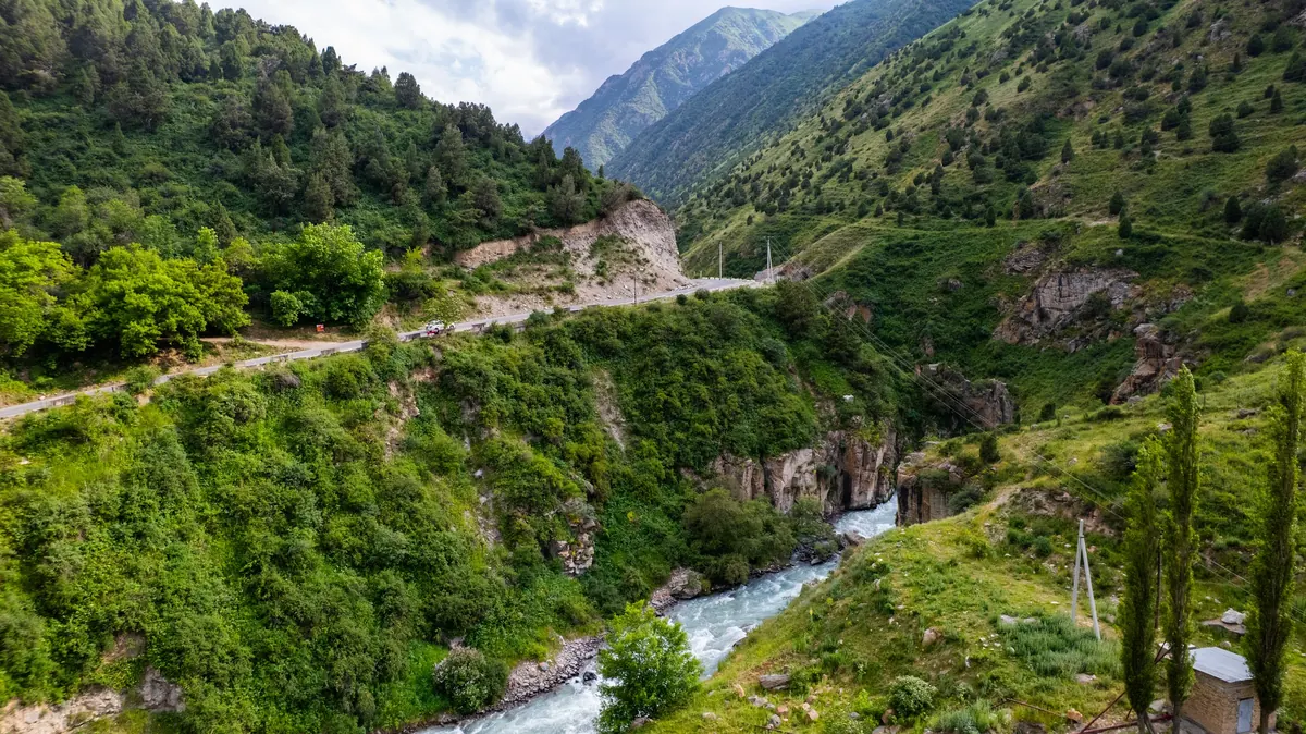 Aerial view of the river cutting through a narrow rocky gorge between green slopes, with a road along the hillside above.